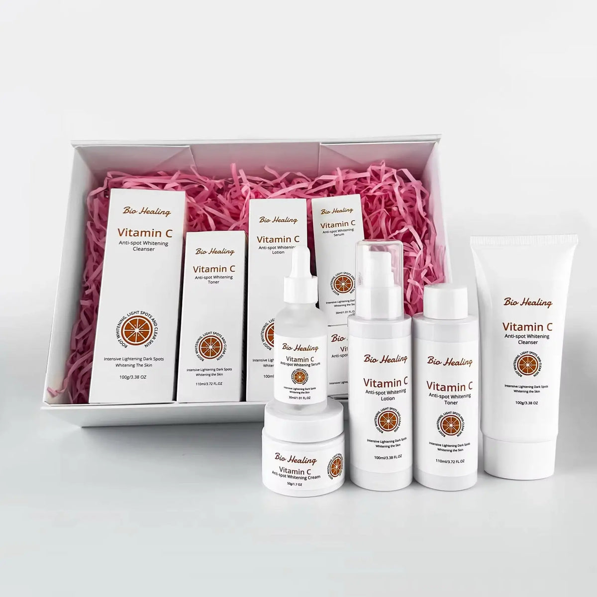 VC Dark Spot Whitening Set with white Vitamin C skincare bottles and boxes, featuring gold labels and pink filler in a gift box.